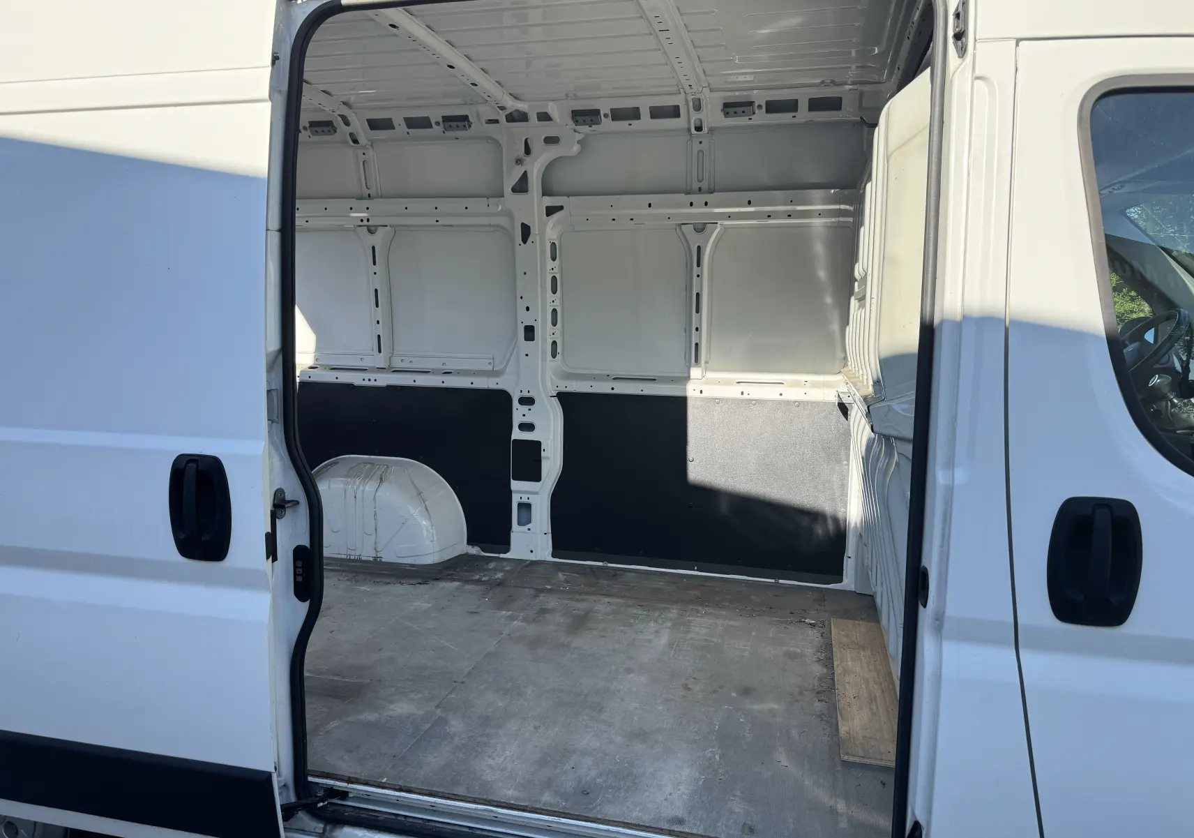 Vue intérieure côté droit du Peugeot Boxer Fourgon blanc 2019, montrant l'espace de chargement vide avec cloison partielle noire.