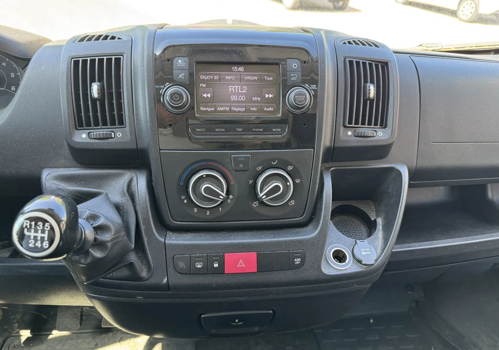 Tableau de bord noir du Peugeot Boxer Fourgon 2019 avec commandes climatisation et radio affichant RTL2, vue frontale intérieure.