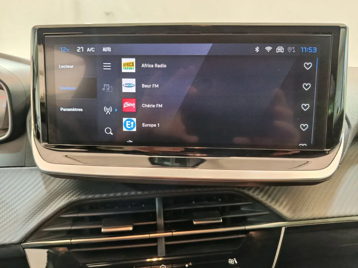 Écran tactile central de la Peugeot 208 PureTech 100 S&S Allure 2025 affichant une liste de stations radio.