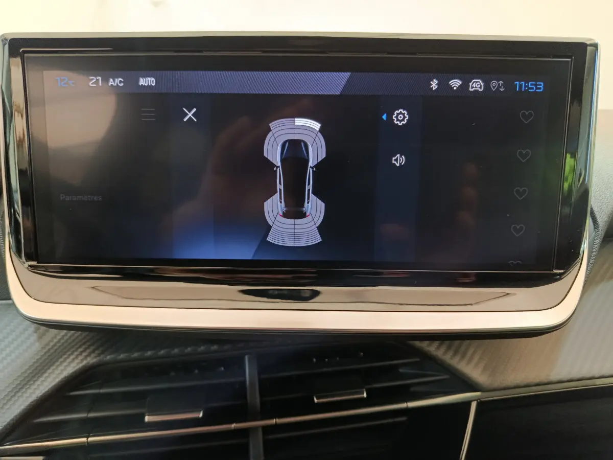 Écran tactile central affichant la vue aérienne du système d'aide au stationnement dans une Peugeot 208 gris clair.