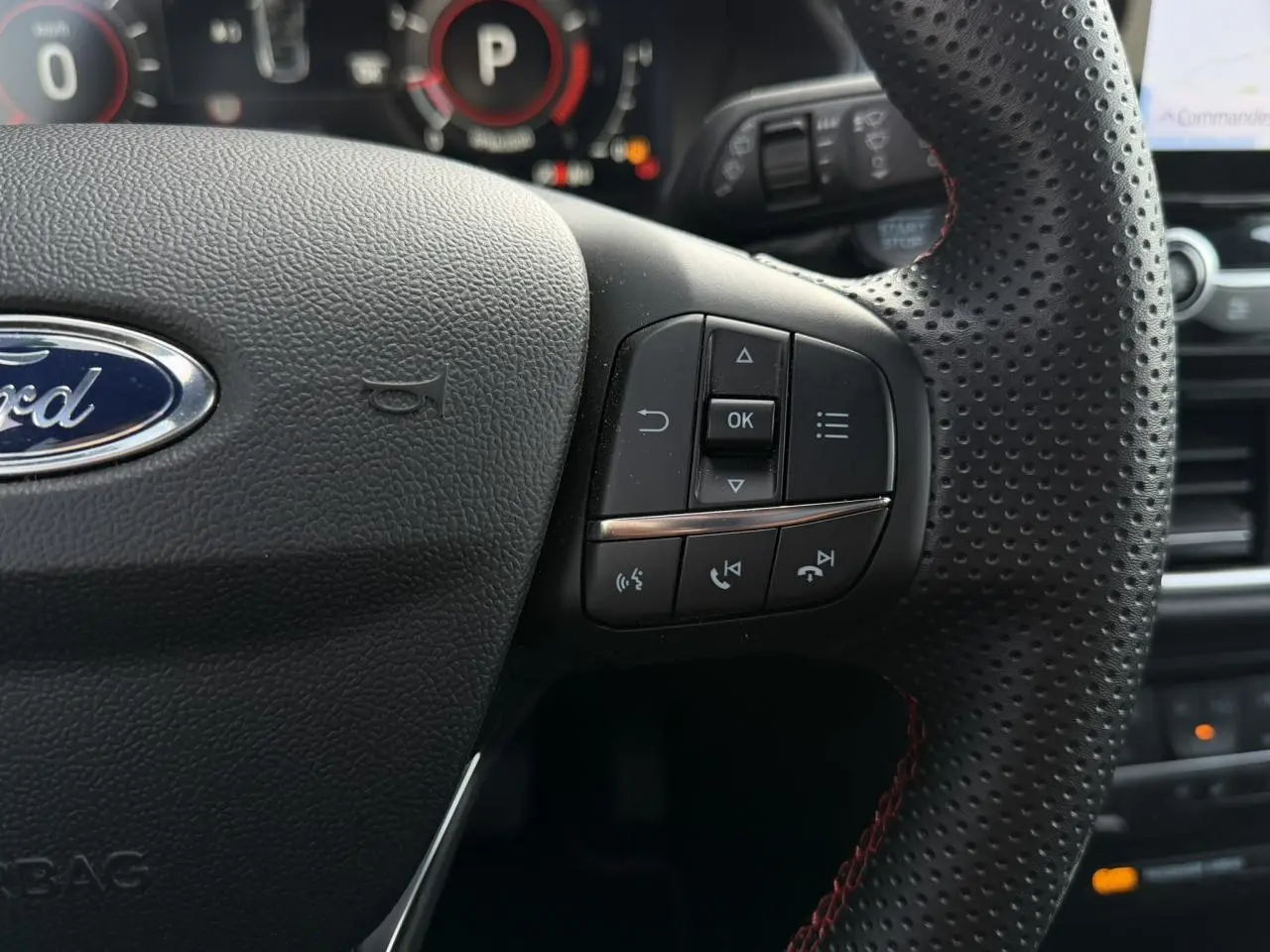 Gros plan sur le volant perforé noir avec commandes intégrées et tableau de bord numérique du Ford Puma 2024.