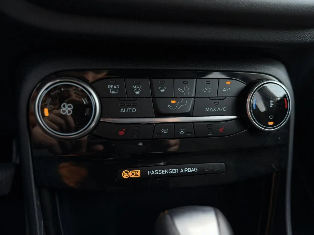 Gros plan sur la console centrale du Ford Puma gris magnétique, avec commandes climatisation et sièges chauffants allumés.