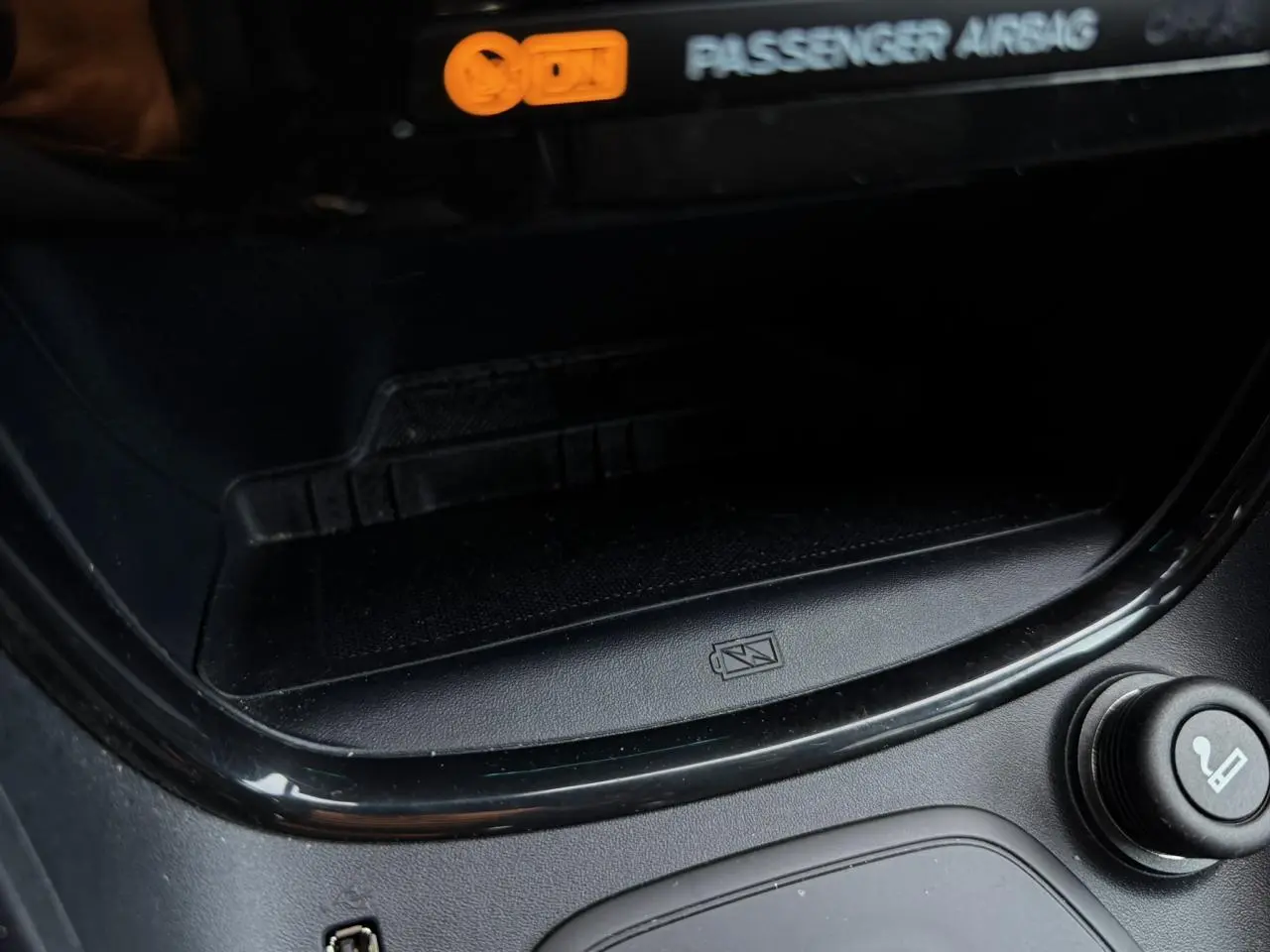 Gros plan sur la console centrale noire du Ford Puma 2024, montrant le chargeur smartphone à induction et allume-cigare.