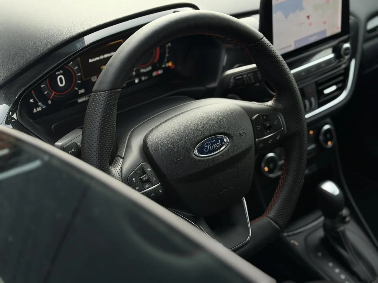 Vue intérieure centrée sur le volant ST-Line perforé du Ford Puma 2024 avec tableau de bord numérique et écran tactile.