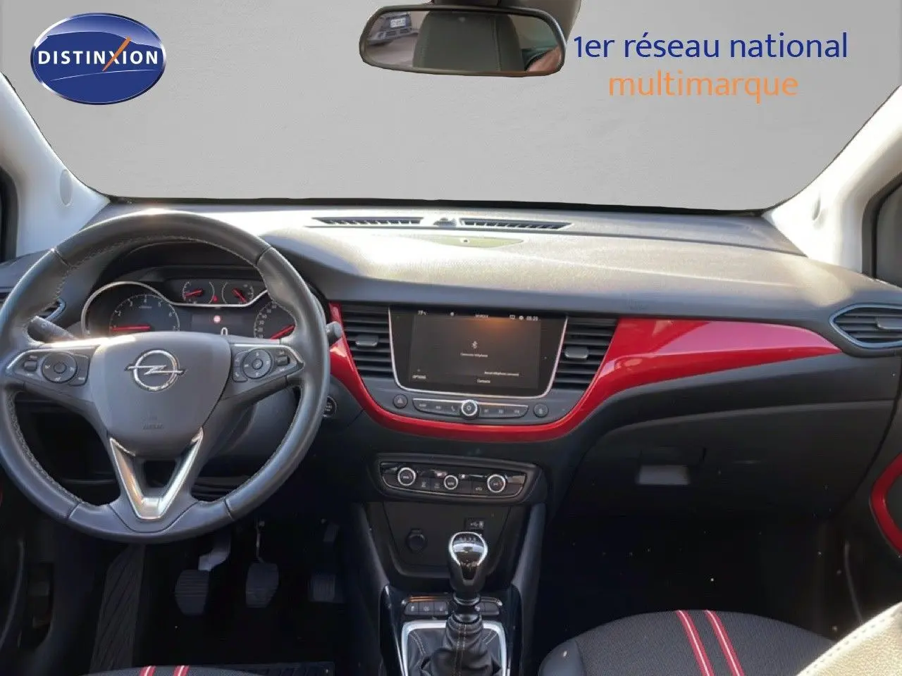 Vue intérieure avant de l’Opel Crossland 2023, tableau de bord noir avec inserts rouges et volant cuir multifonction.