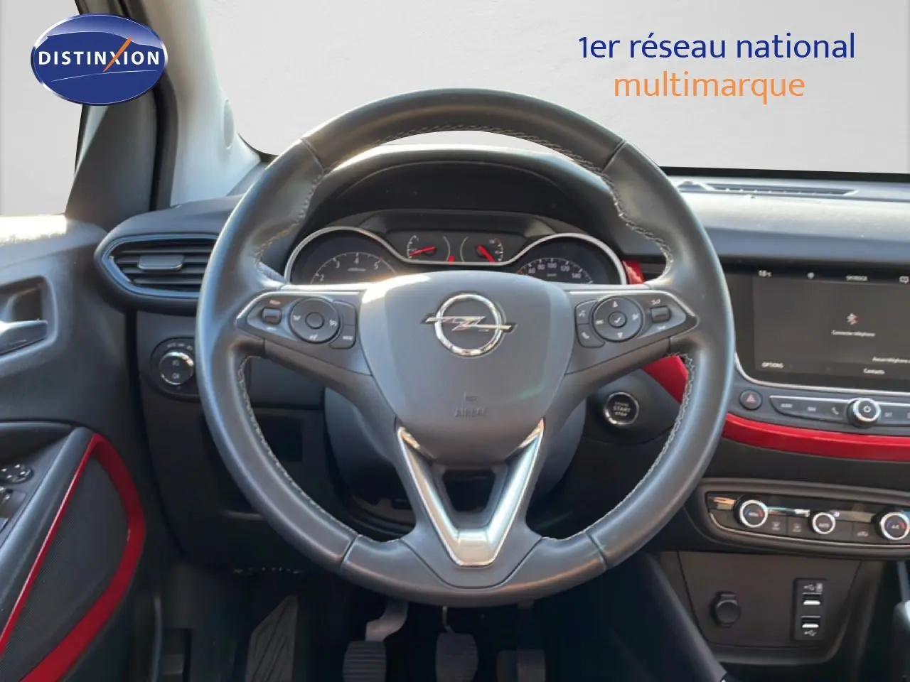 Vue intérieure centrée sur le volant cuir noir de l’Opel Crossland 2023 avec détails rouges sur la planche de bord.