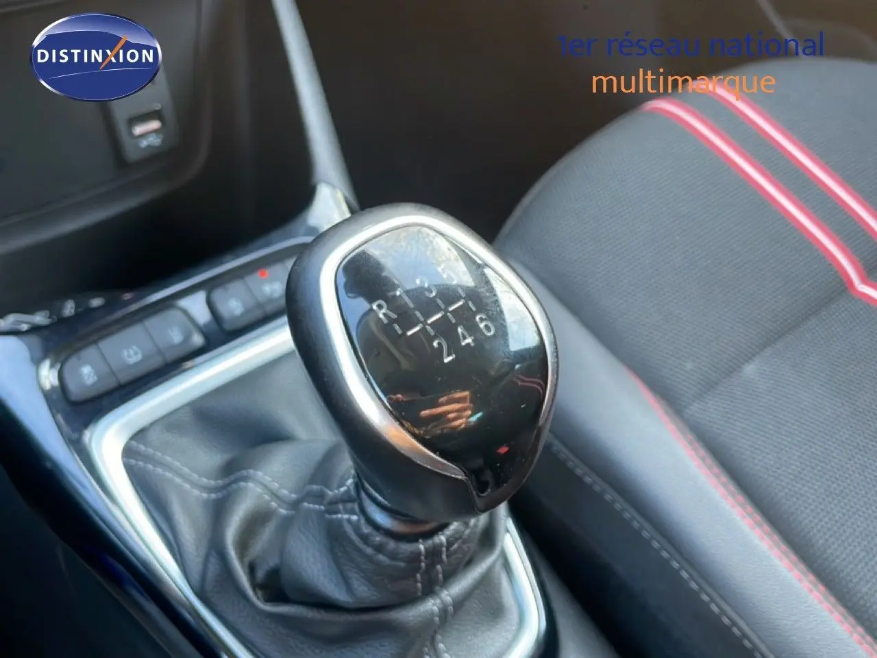 Gros plan sur le levier de vitesses manuel noir et argenté de l’Opel Crossland 2023, avec siège tissu noir et surpiqûres rouges.