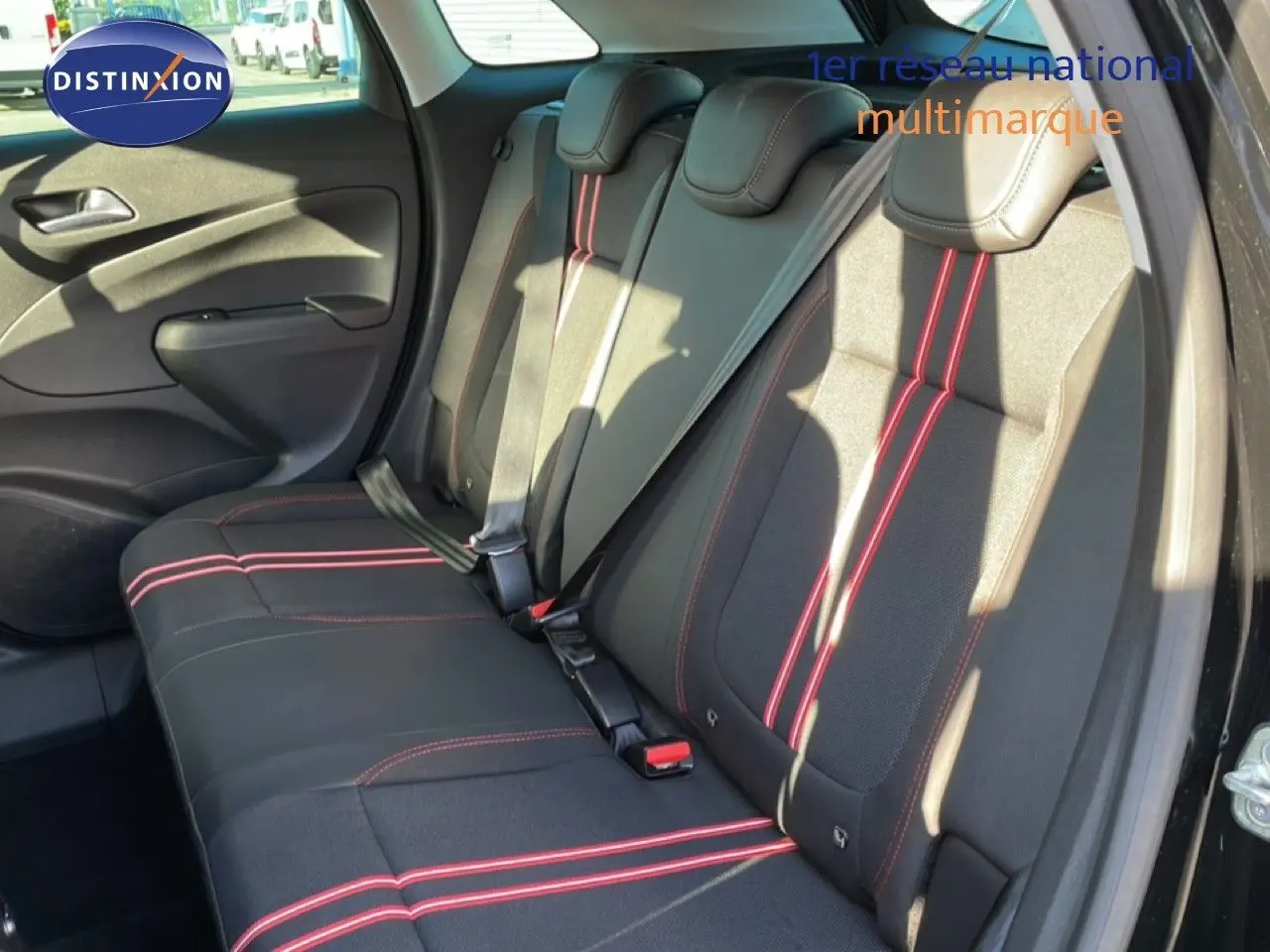 Vue intérieure du siège arrière de l'Opel Crossland noir Karbon avec surpiqûres rouges et ceintures de sécurité visibles.