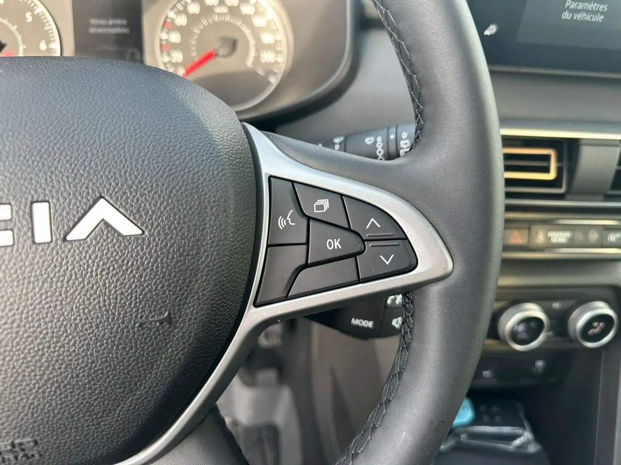 Gros plan sur le volant noir avec commandes multifonctions et tableau de bord de la Dacia Sandero III Stepway.