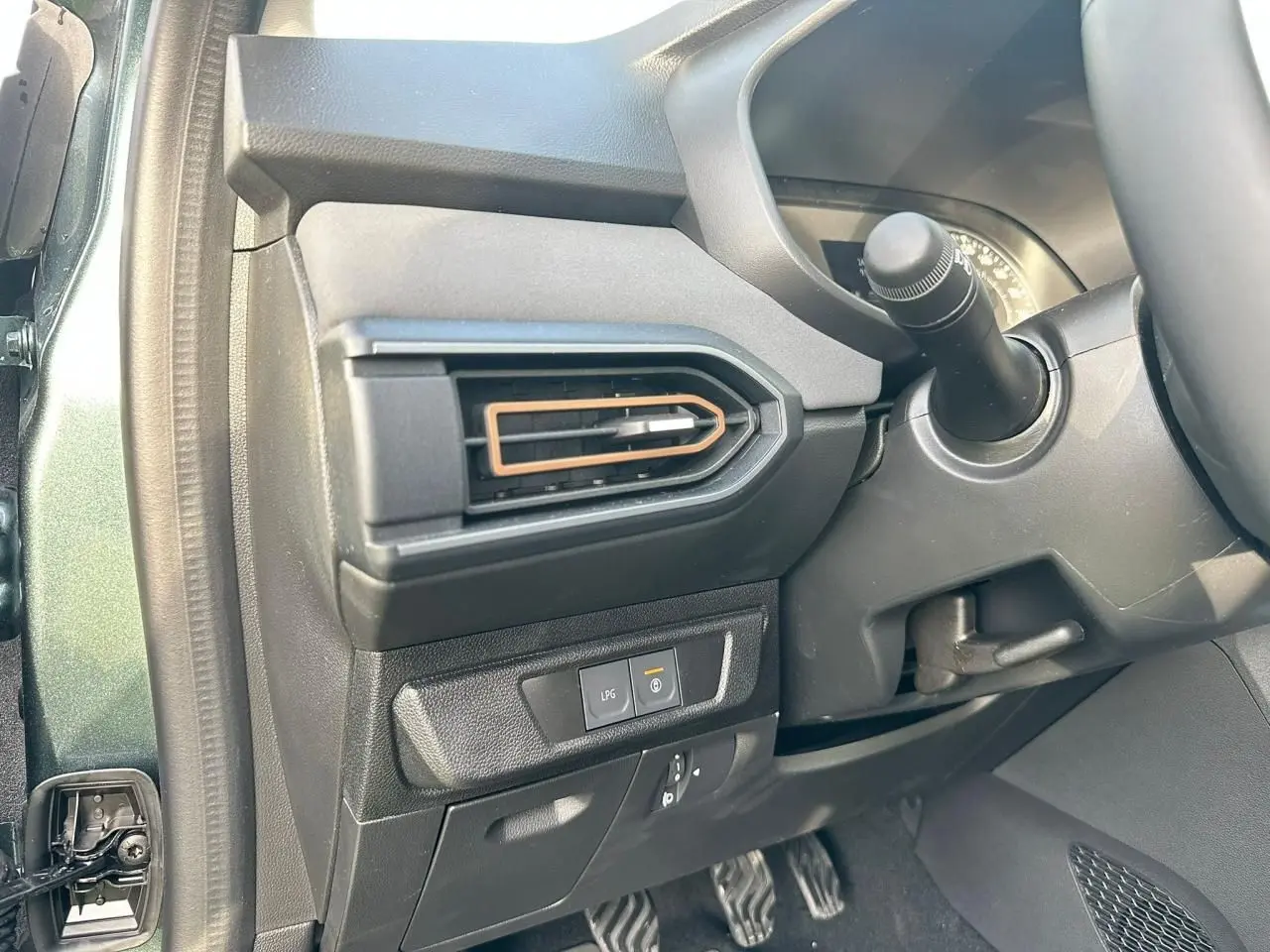 Détail intérieur côté gauche avec sortie d’air brun cuivré et bouton de gestion GPL sur Dacia Sandero Vert Cèdre 2025.