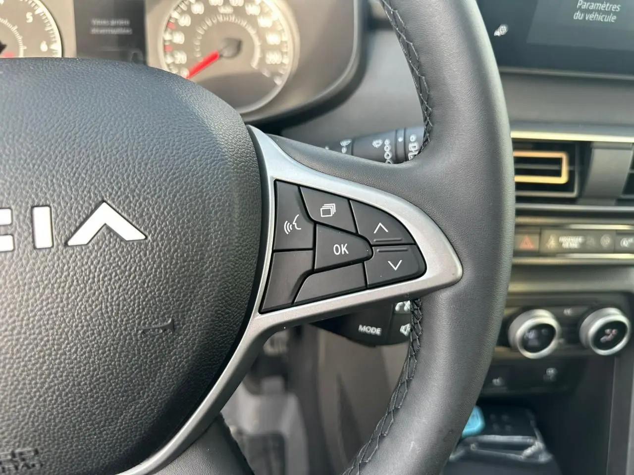 Gros plan sur le volant noir de la Dacia Sandero III Stepway avec commandes multifonctions et tableau de bord partiel.