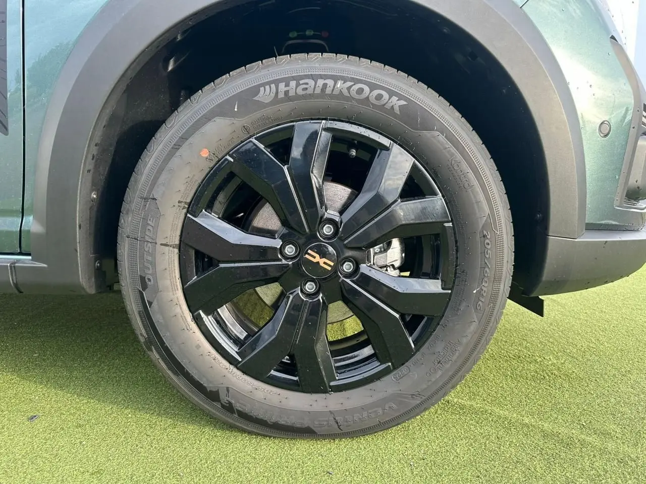 Gros plan sur la roue avant gauche noire brillante d'une Dacia Sandero Stepway 2025 Vert Cèdre avec pneu Hankook.