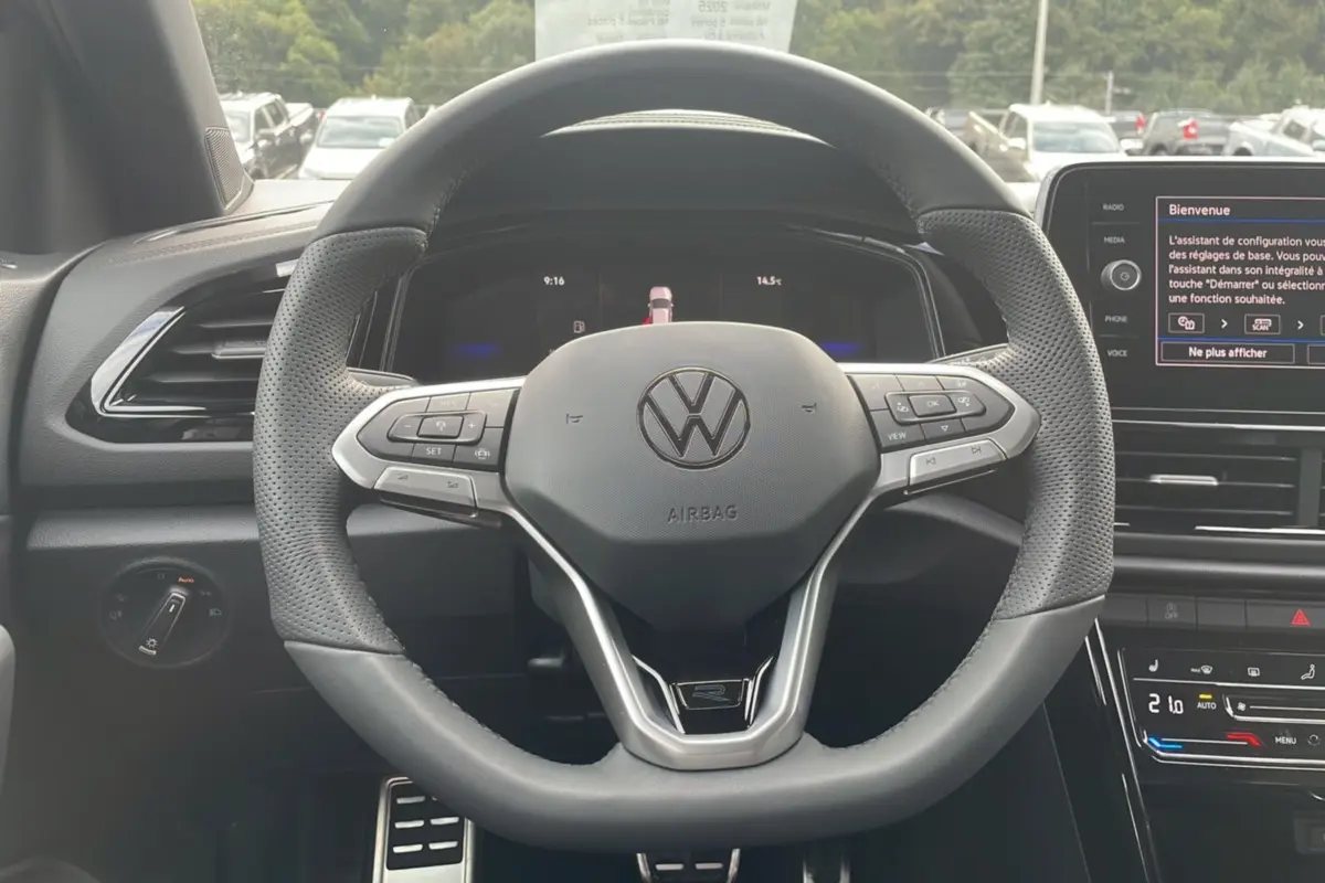 Vue intérieure centrée sur le volant cuir multifonctions du Volkswagen T-Roc noir grenadilla avec tableau de bord digital.