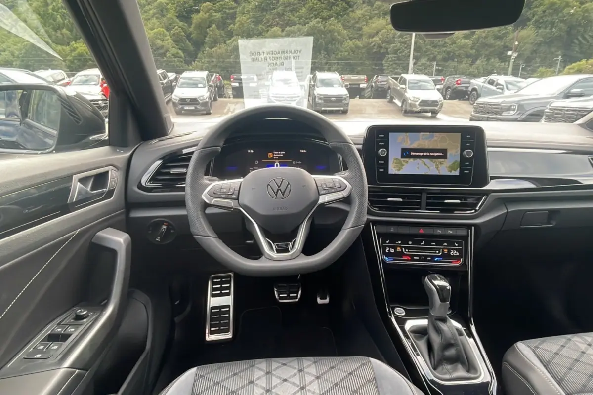 Vue intérieure avant du Volkswagen T-Roc TDI 150 DSG7 R-Line Black, volant cuir multifonctions et écran tactile GPS visible.