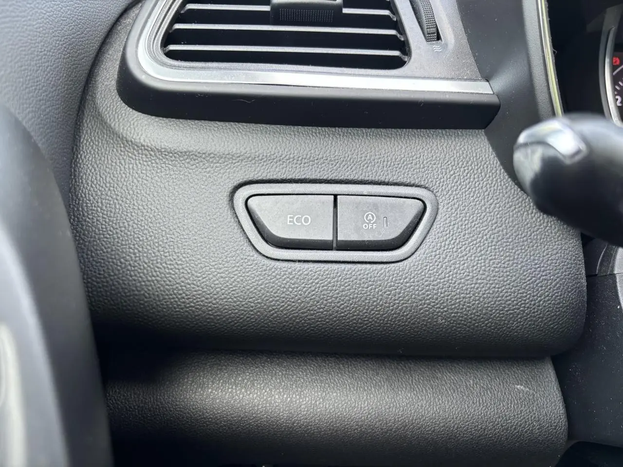 Gros plan sur les boutons ECO et arrêt du système start-stop du tableau de bord noir du Renault Kadjar gris foncé.