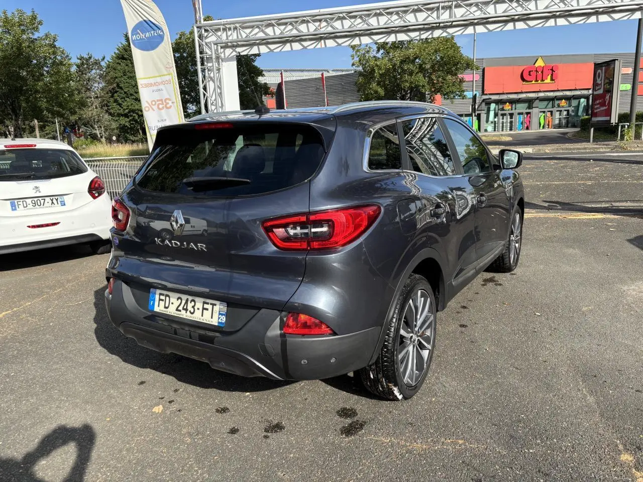 Vue 3/4 arrière droite d'un Renault Kadjar gris foncé garé, avec vitres surteintées et feux arrière LED distinctifs.