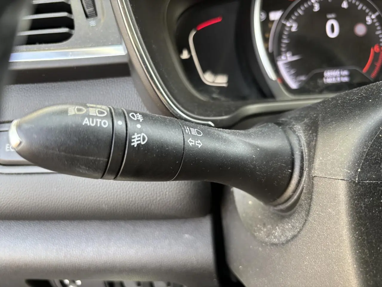 Gros plan sur la commande des phares et clignotants dans l'habitacle du Renault Kadjar gris foncé 2018.