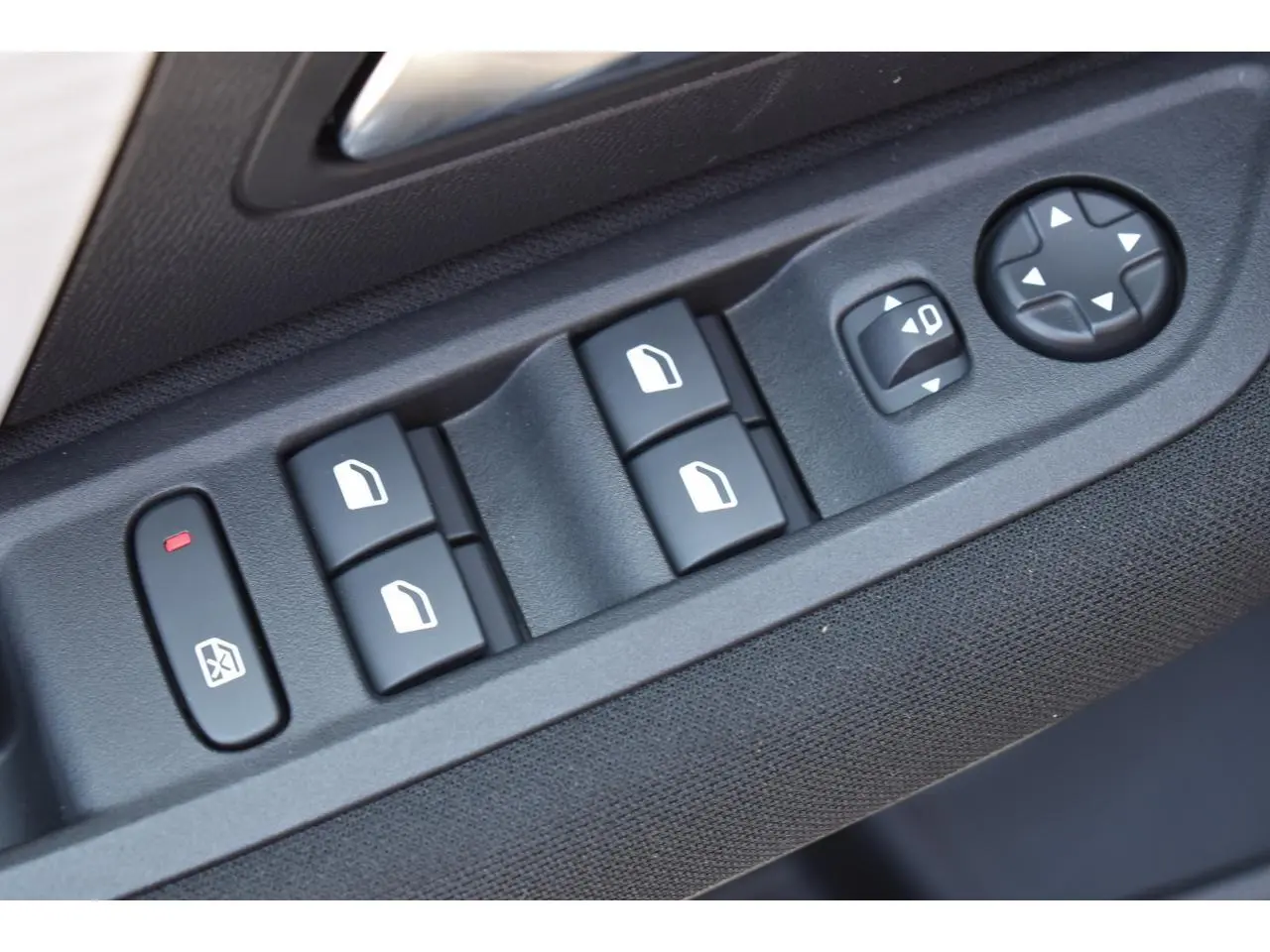Gros plan sur les commandes de lève-vitres et réglages des rétroviseurs côté conducteur d'une Citroën C4 noire.