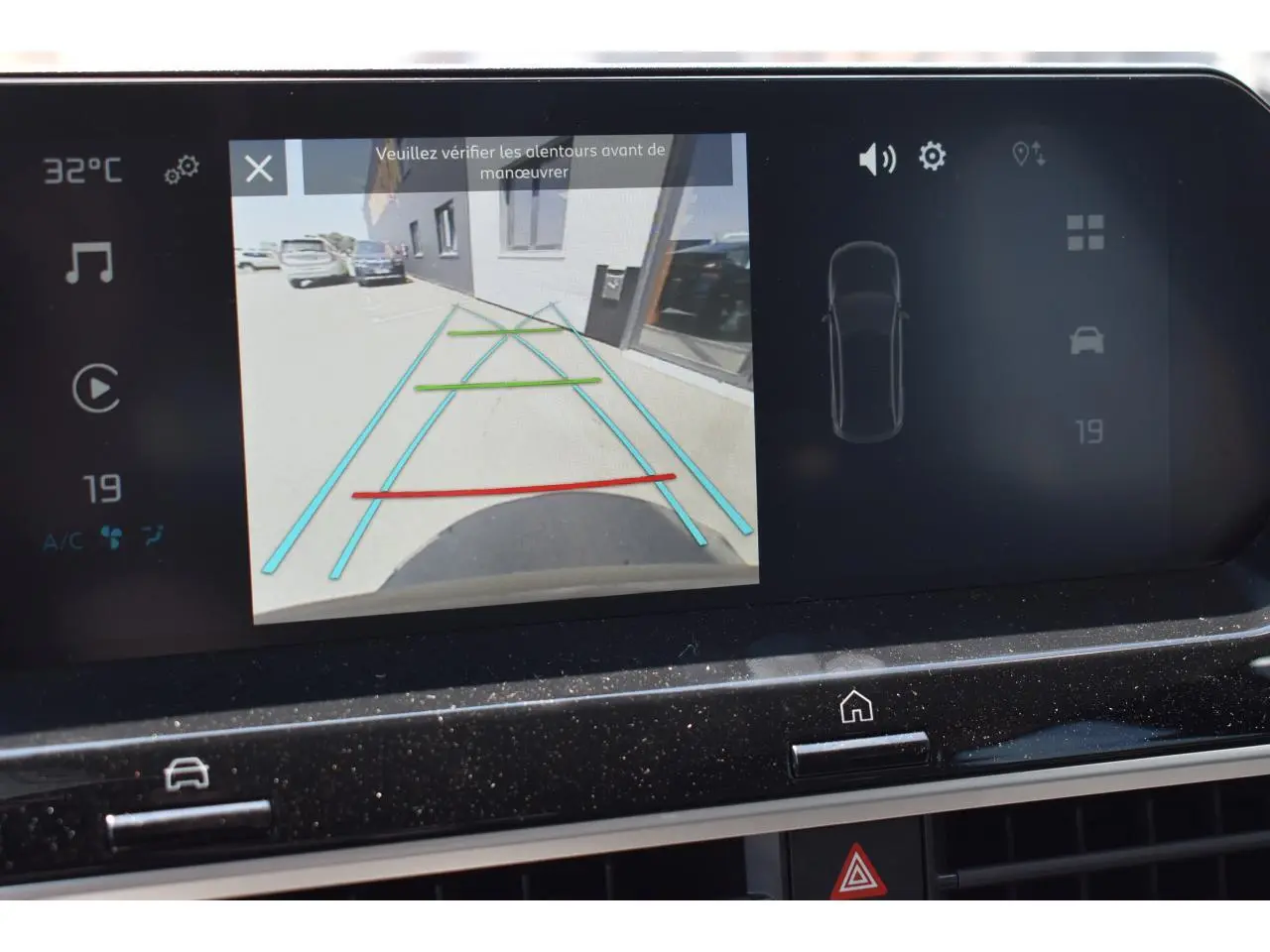 Écran central tactile montrant la caméra de recul d'une Citroën C4 Hybride noire, avec lignes de guidage colorées.