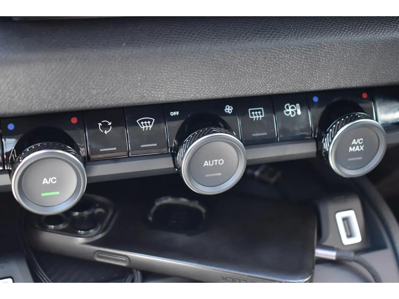 Gros plan sur les commandes de climatisation automatique de la Citroën C4 Hybride noire, avec boutons rotatifs et affichages LED.