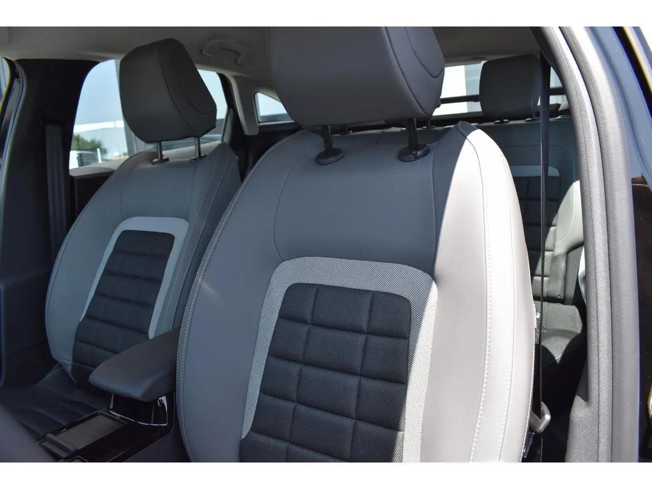 Gros plan sur les sièges avant gris et noirs du Citroën C4 Hybride 136 e-DCS6 Plus 2025, intérieur lumineux.