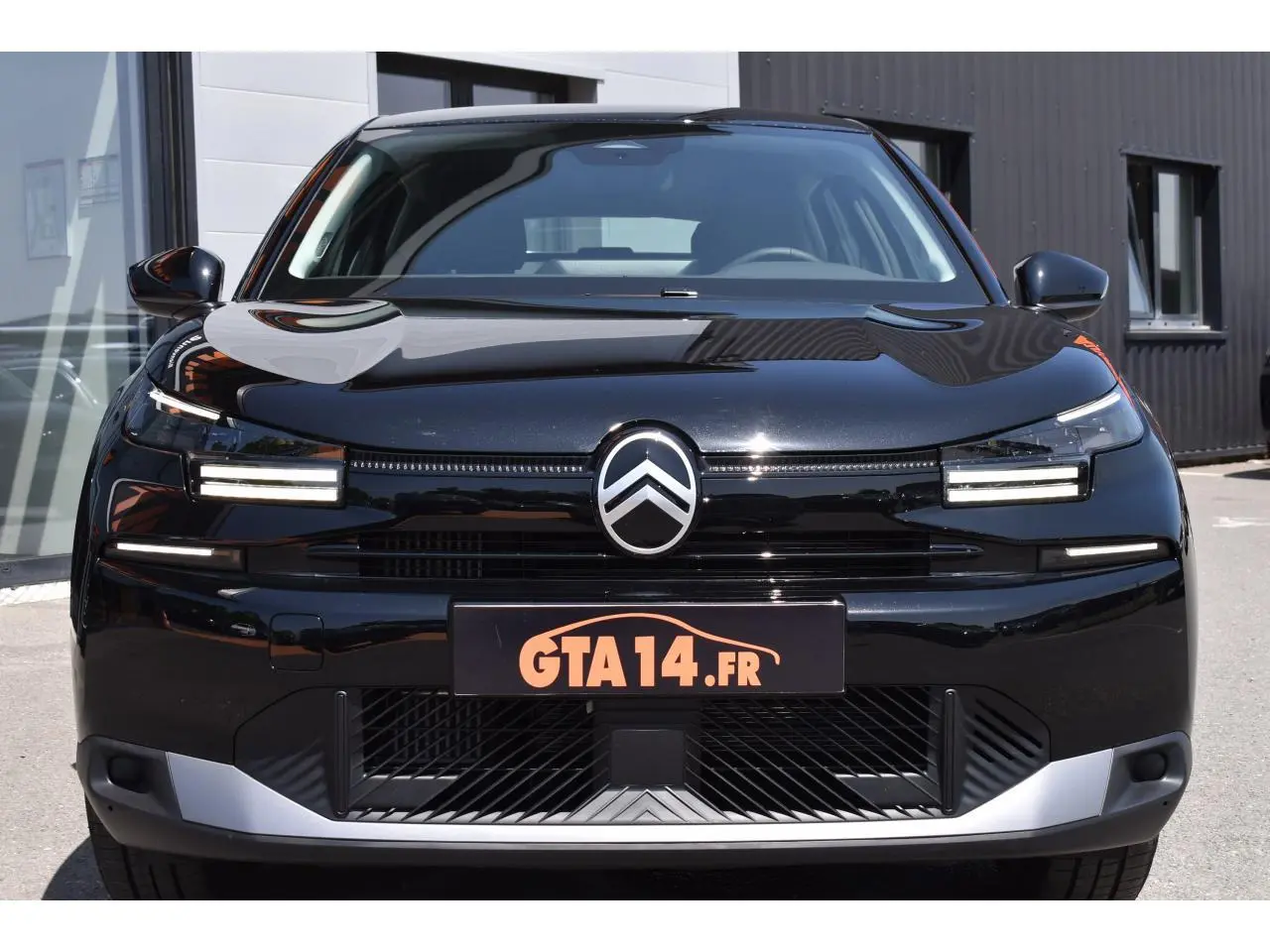Vue frontale d'une Citroën C4 Hybride noire 2025 avec feux LED distinctifs et calandre épurée.