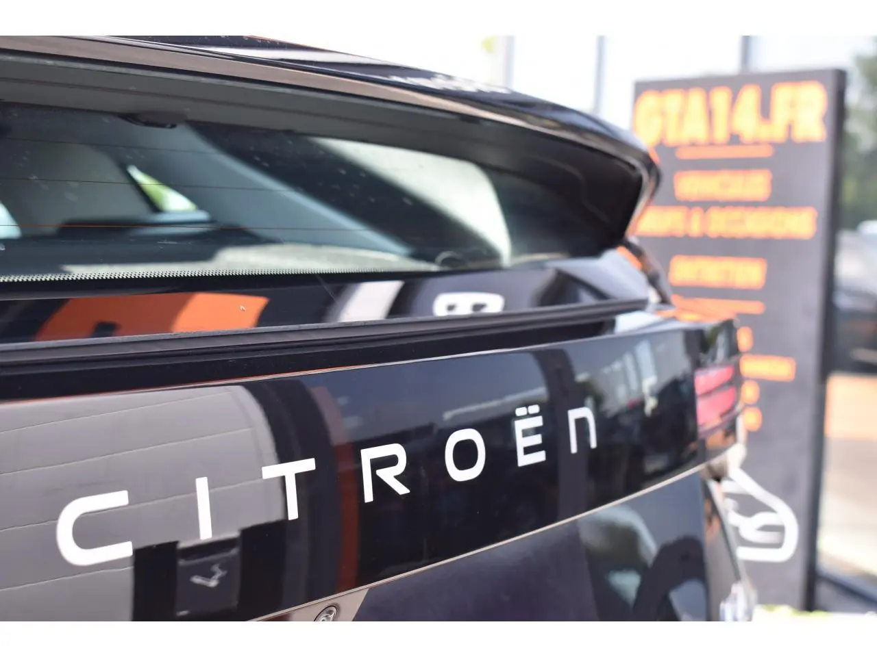 Gros plan sur l'arrière noir brillant d'une Citroën C4 hybride 2025 avec hayon ouvert et logo Citroën visible.