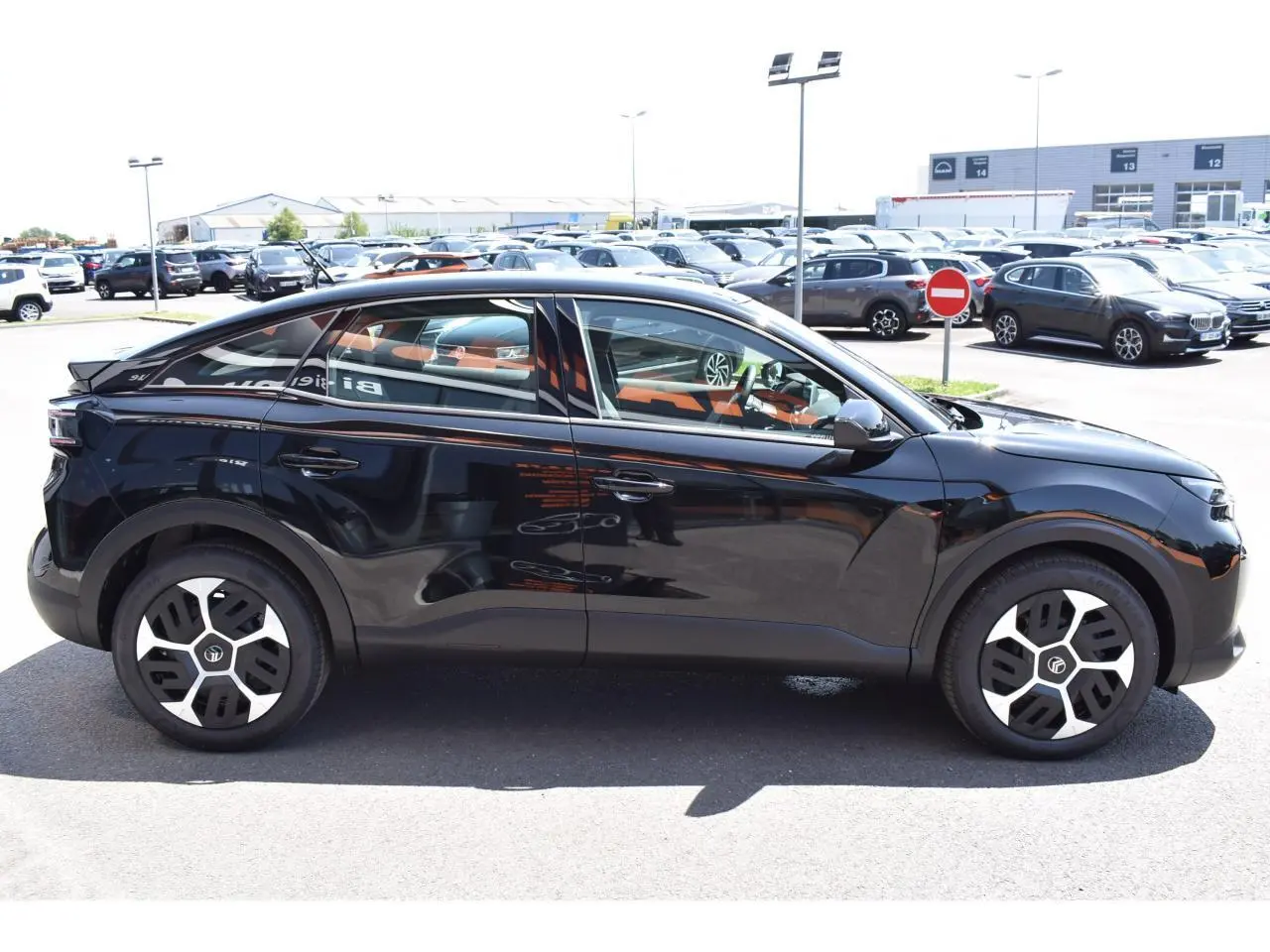 Vue latérale droite d'une Citroën C4 Hybride noire 2025 avec jantes 18 pouces et vitres teintées.