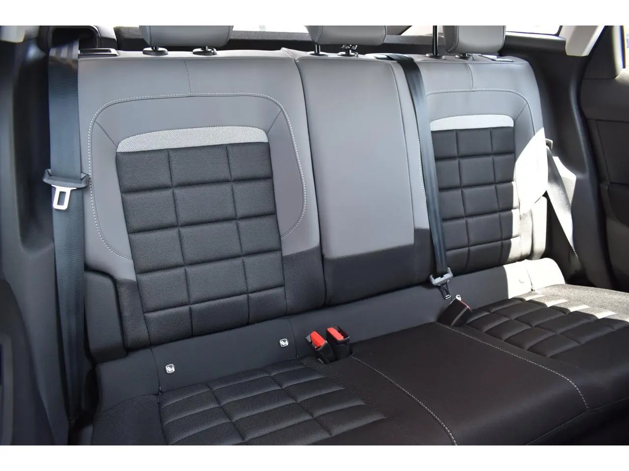 Vue rapprochée des sièges arrière en tissu noir et gris de la Citroën C4 Hybride 2025, avec ceintures de sécurité visibles.