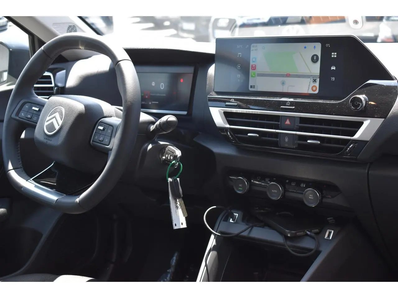Vue intérieure côté conducteur du tableau de bord noir de la Citroën C4 Hybride 2025 avec écran tactile central et volant multifonction.