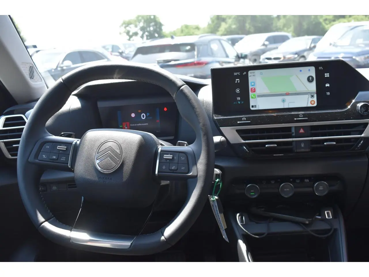 Vue intérieure centrée sur le volant et l’écran tactile du tableau de bord du Citroën C4 Hybride noir 2025.
