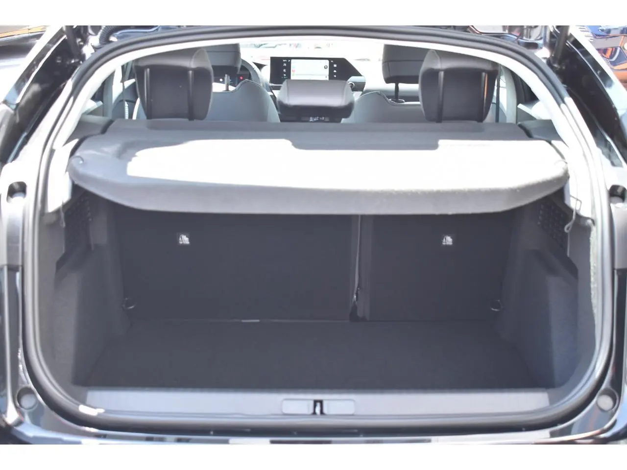 Vue arrière du coffre ouvert d'une Citroën C4 Hybride 136 e-DCS6 Plus noire, avec tablette cache-bagages et intérieur visible.