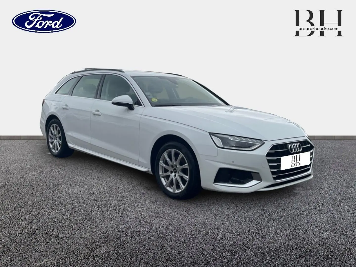 Audi A4 Avant blanc glacier métallisé vue 3/4 avant droit, avec jantes alu et barres de toit visibles.