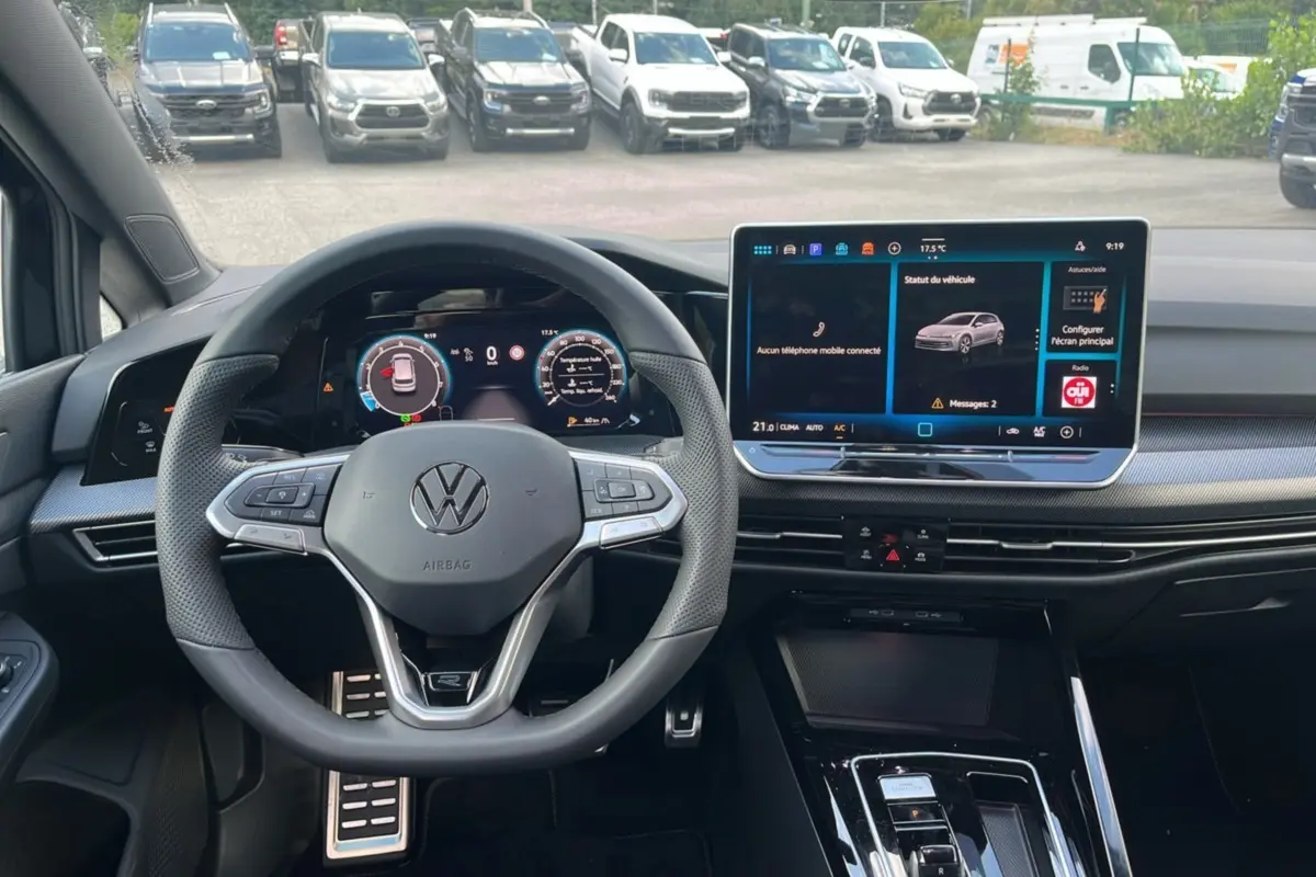 Vue intérieure centrée sur le volant cuir multifonctions et l'écran tactile du tableau de bord de la Volkswagen Golf noir ebène.