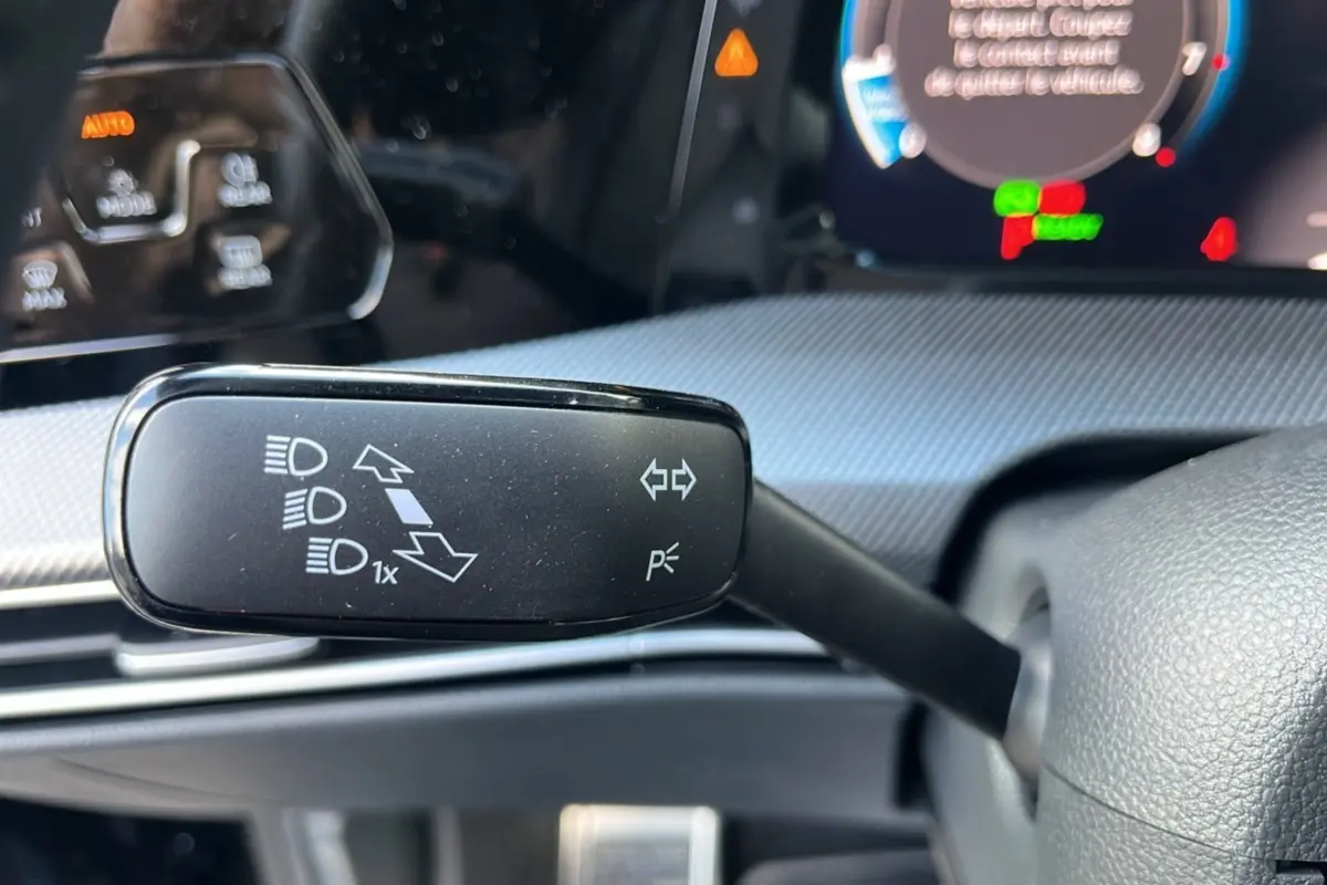 Gros plan sur la commande de clignotants à gauche du volant dans l’habitacle d’une Volkswagen Golf noir ébène 2026.