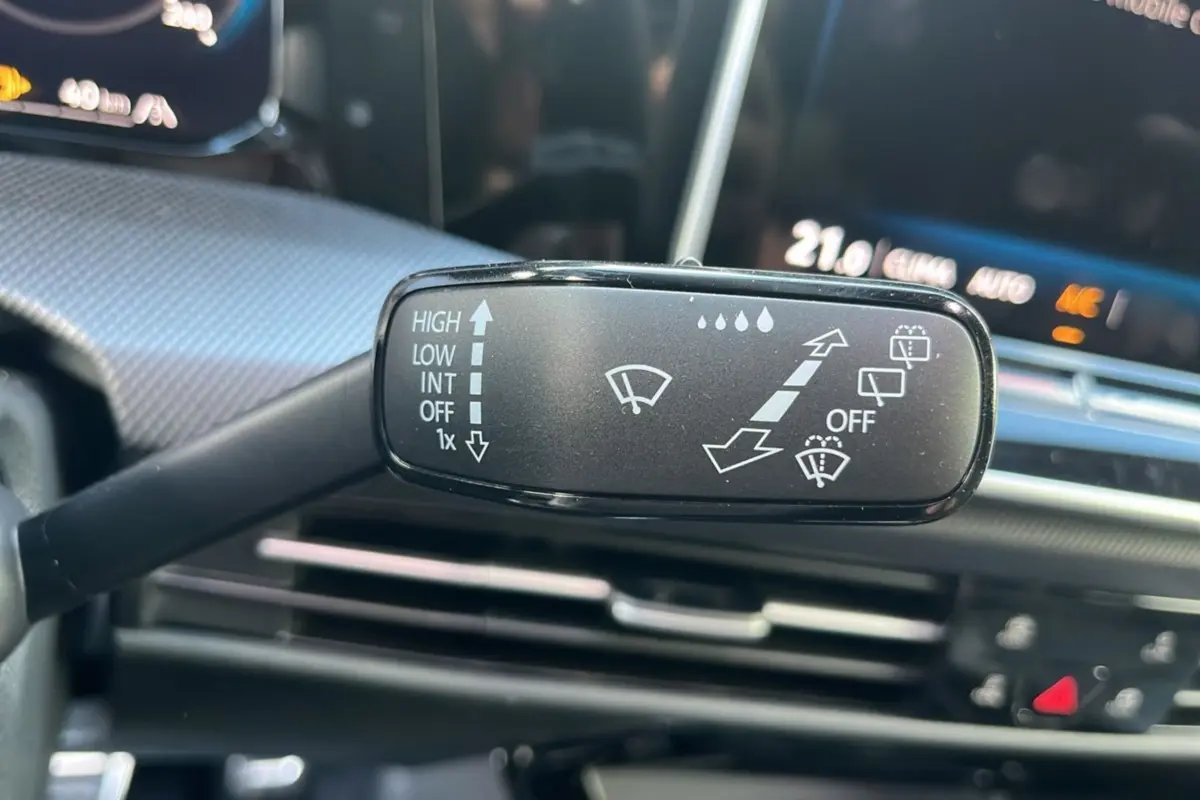 Gros plan sur la commande d’essuie-glace côté gauche du volant d’une Volkswagen Golf noir ébène, tableau de bord en arrière-plan.