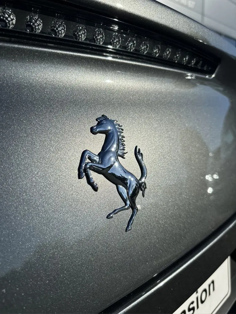 Gros plan sur l'emblème cheval cabré noir sur la calandre gris foncé d'une Ferrari GTC4 Lusso 2017.