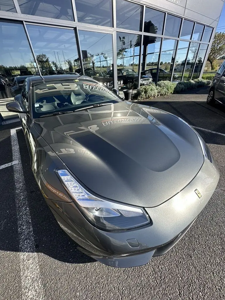 Vue 3/4 avant d'une Ferrari GTC4 Lusso gris foncé brillante, avec ses phares LED et son capot sculpté bien visibles.