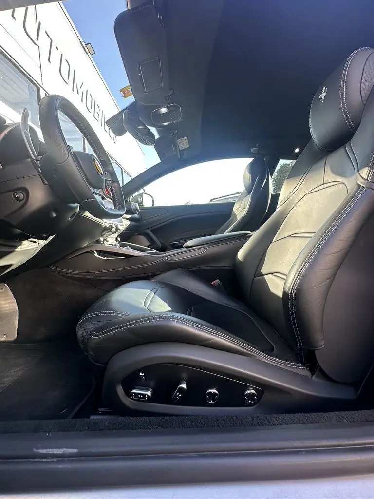 Intérieur côté conducteur de la Ferrari GTC4 Lusso 2017, sièges cuir noirs avec logo cheval cabré brodé sur appuie-tête.