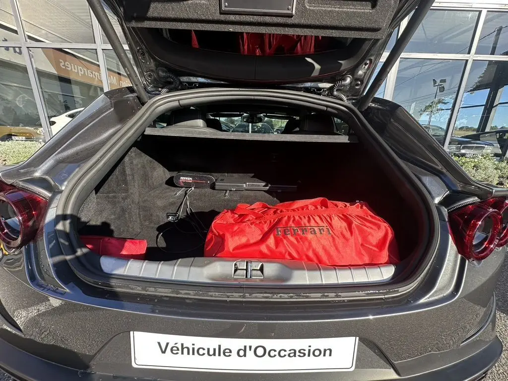 Vue arrière ouverte d'une Ferrari GTC4 Lusso gris foncé de 2017, coffre avec sac rouge Ferrari visible.