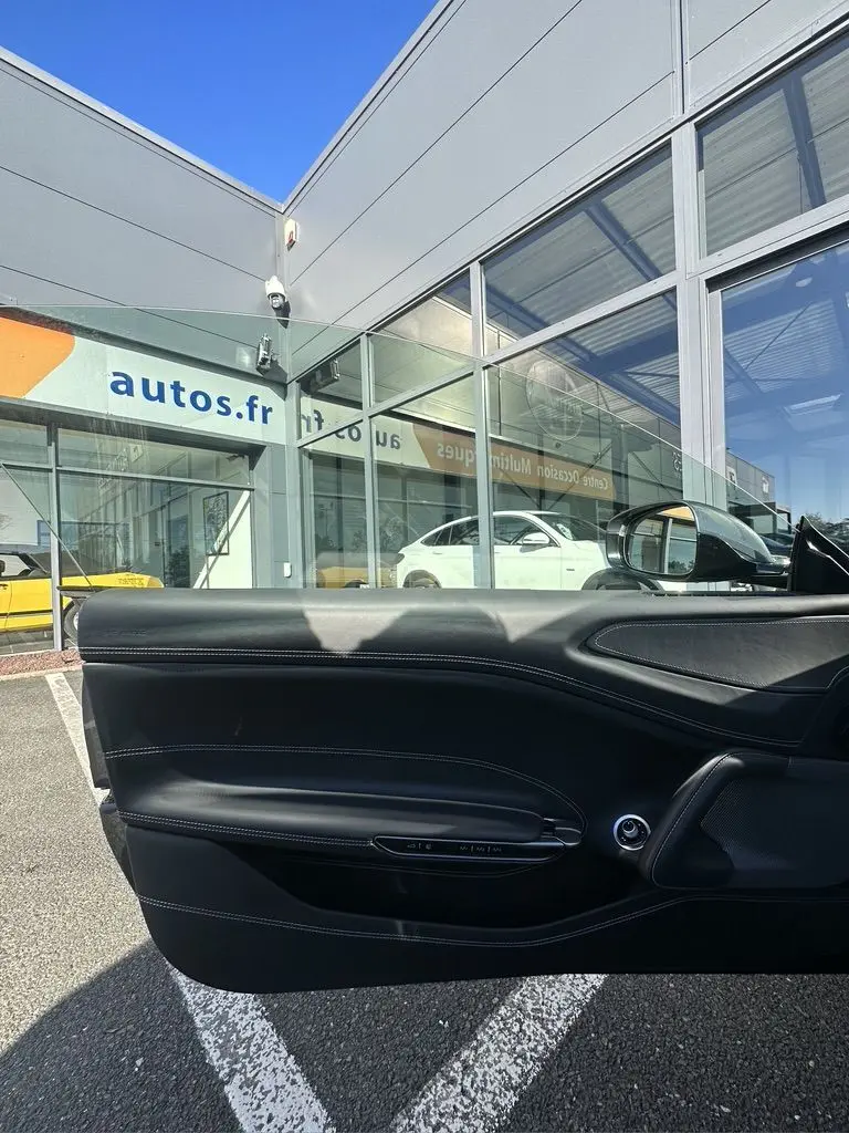 Vue intérieure de la porte côté gauche en cuir noir de la Ferrari GTC4 Lusso gris foncé 2017 stationnée en extérieur.