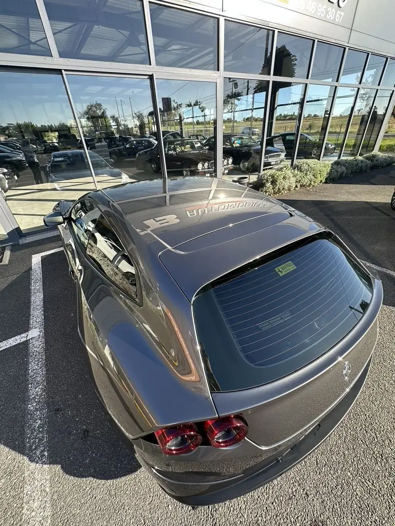 Vue 3/4 arrière d'une Ferrari GTC4 Lusso gris foncé avec feux arrière ronds et toit panoramique réfléchissant.