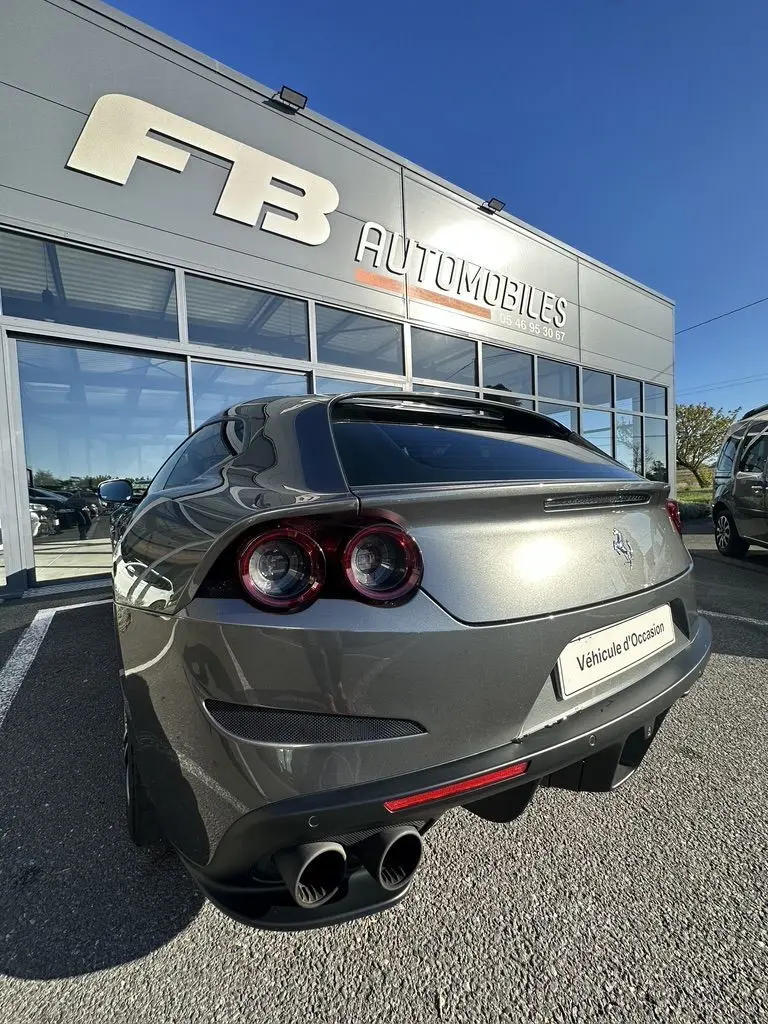 Vue 3/4 arrière droite d'une Ferrari GTC4 Lusso gris foncé avec feux ronds doubles et double sortie d'échappement.