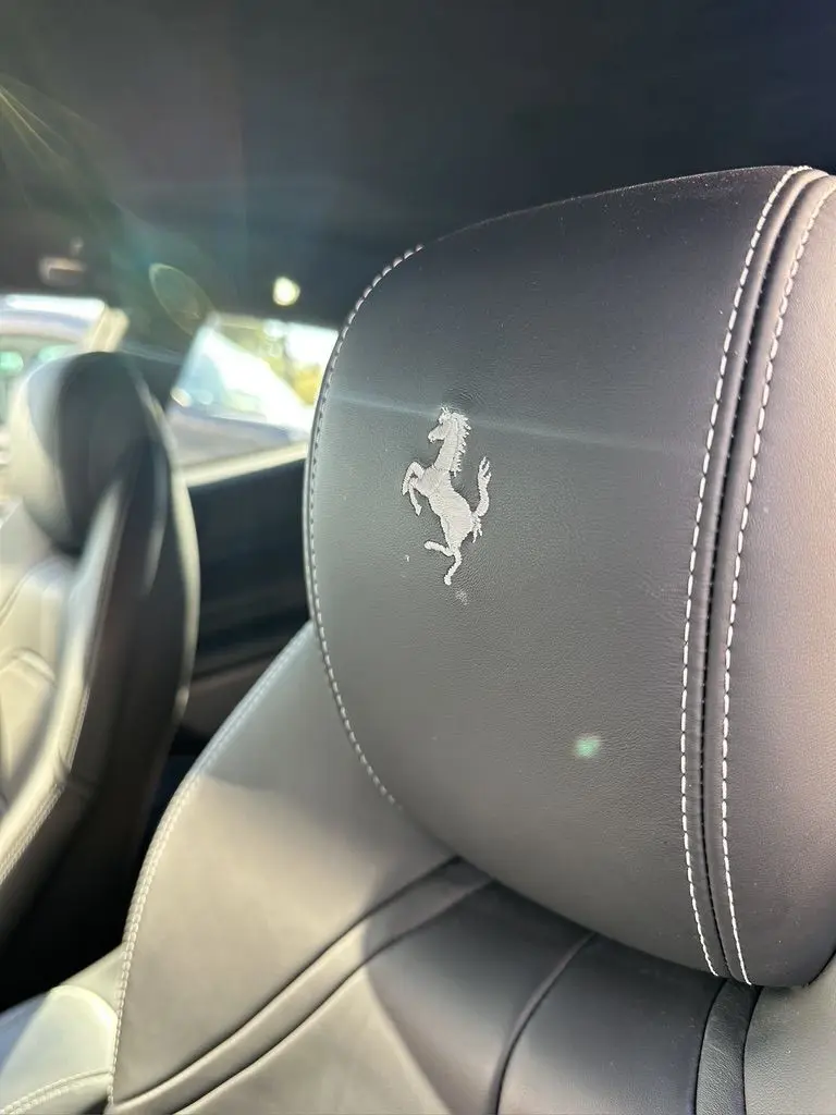 Gros plan sur l'appui-tête en cuir noir avec le cheval cabré brodé à l'intérieur d'une Ferrari GTC4 Lusso 2017.