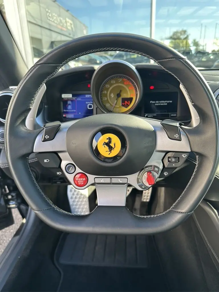 Vue rapprochée du volant noir de la Ferrari GTC4 Lusso 2017 avec logo jaune et tableau de bord digital.