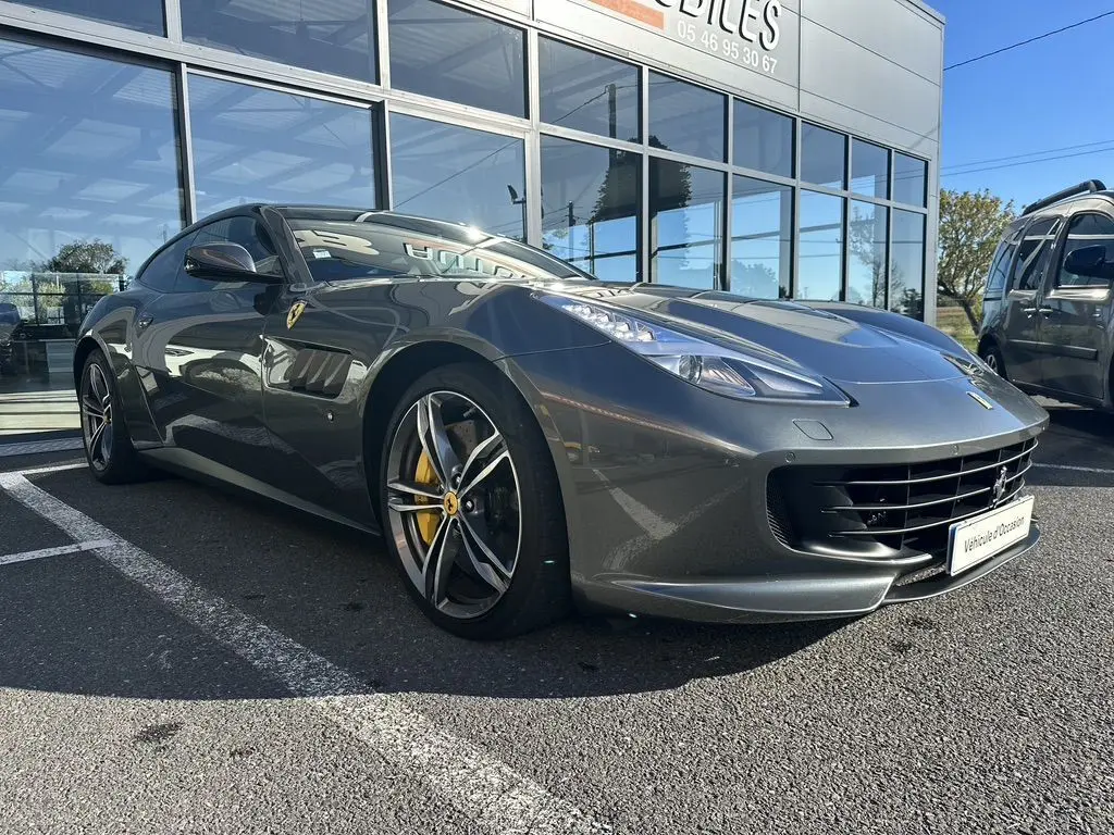 Ferrari GTC4 Lusso gris foncé vue 3/4 avant droit, avec jantes sport et étriers de frein jaunes visibles.