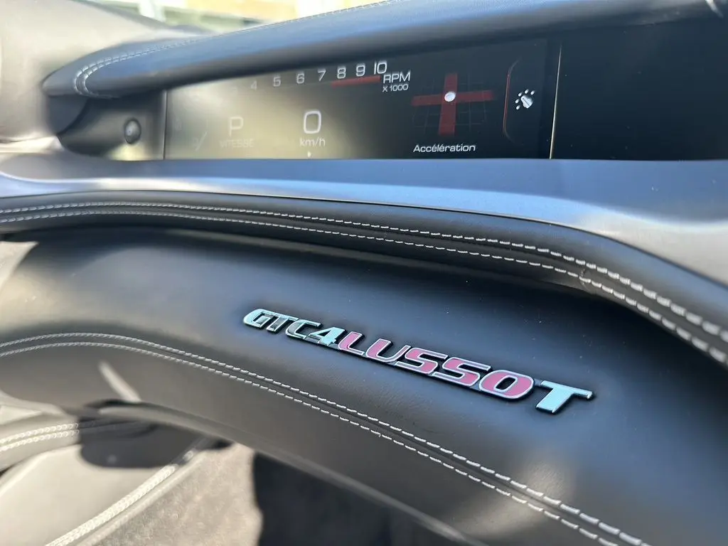Détail intérieur du tableau de bord de la Ferrari GTC4 Lusso T 3.9 V8, avec logo et affichage numérique du compte-tours.