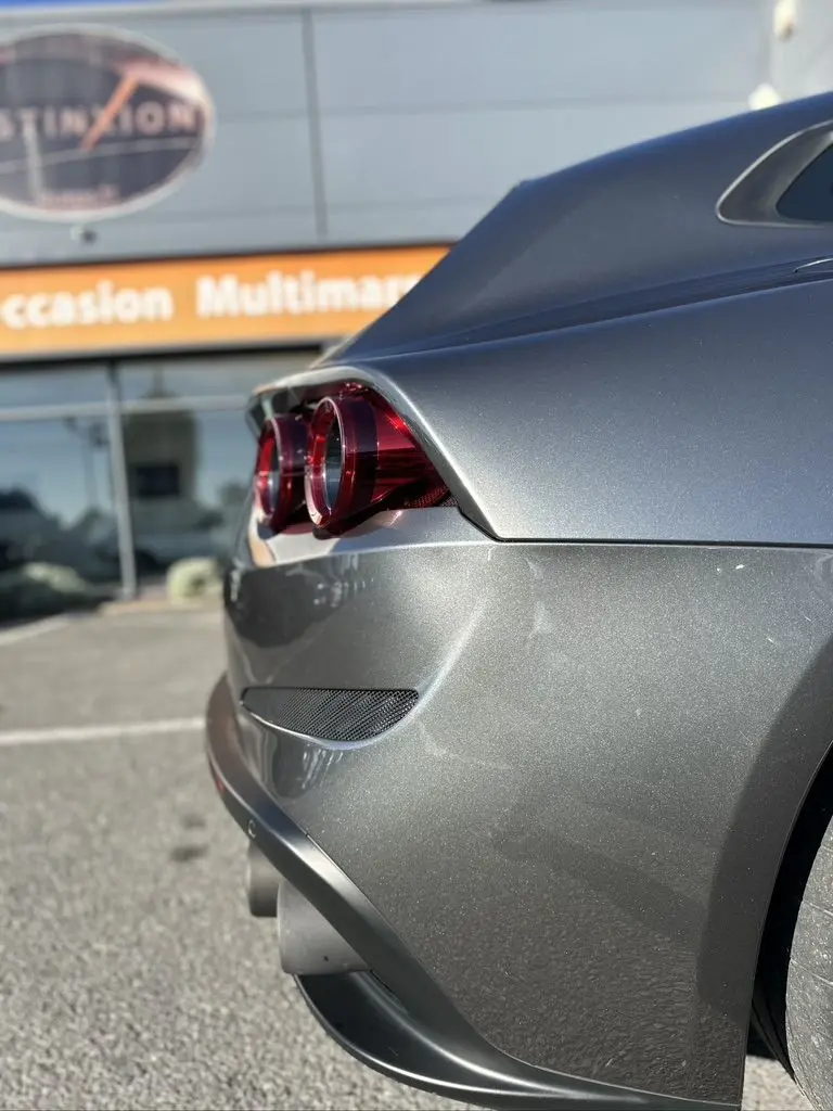 Vue 3/4 arrière droit d'une Ferrari GTC4 Lusso gris foncé mettant en valeur ses feux ronds et lignes fluides.