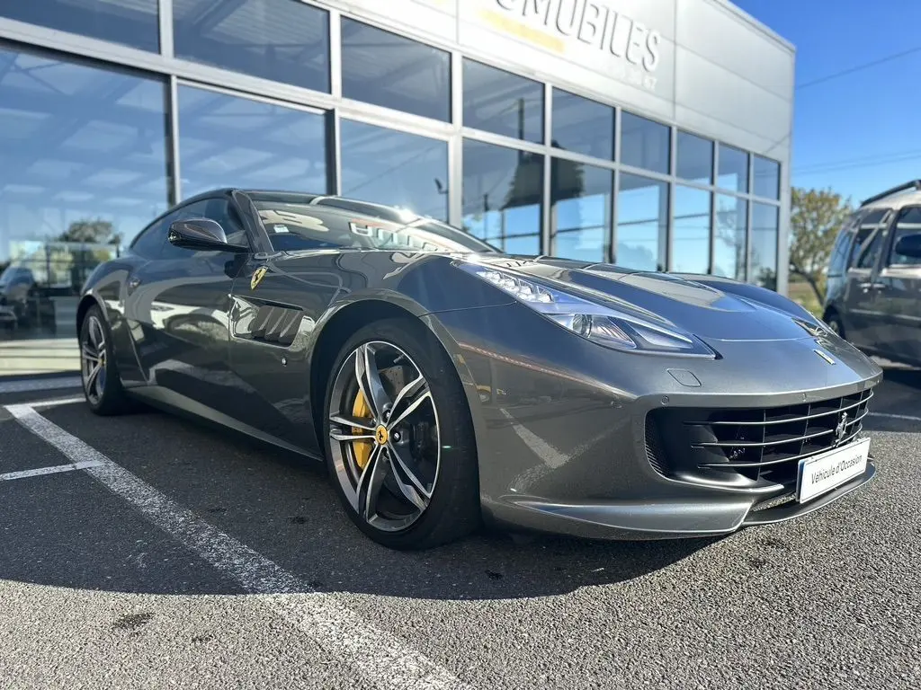 Ferrari GTC4 Lusso gris foncé vue 3/4 avant droit, jantes sport et étriers de frein jaunes visibles.