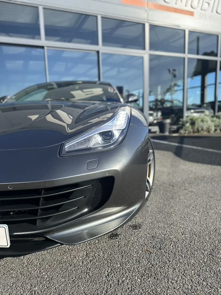 Vue 3/4 avant droit d'une Ferrari GTC4 Lusso gris foncé mettant en valeur son phare et la calandre sportive.